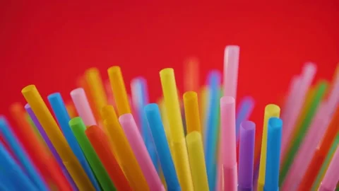 Plastic colored cocktail beverage tubes rotate on a red background Stock Footage 130464037