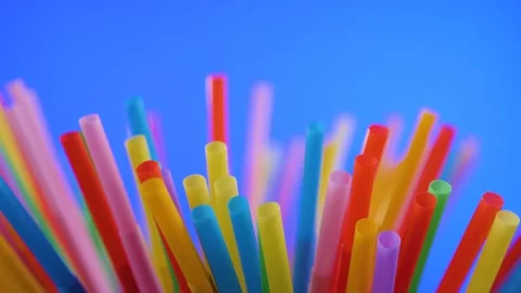 Plastic colored cocktail beverage tubes rotate on a blue background Stock Footage 130822437