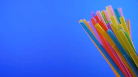 Plastic colored cocktail beverage tubes rotate on a blue background Stock Footage 131230120