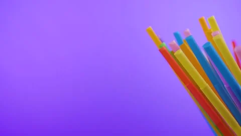Plastic colored cocktail beverage tubes rotate on a violet background Stock Footage 131947804