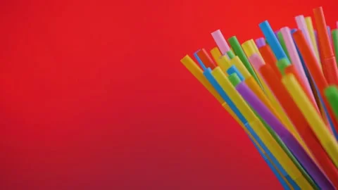 Plastic colored cocktail beverage tubes rotate on a red background Stock Footage 132325108