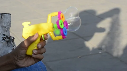 Plastic colorful bubble makers gun in young teenagehand in outdoor area Stock Footage 110273370