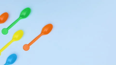 Plastic colorful spoons appear from left side on blue background - Stop motion Stock Footage 134832410