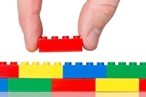 Plastic construction on white Creativity concept. Hand building up lego wa... Stock Photos
