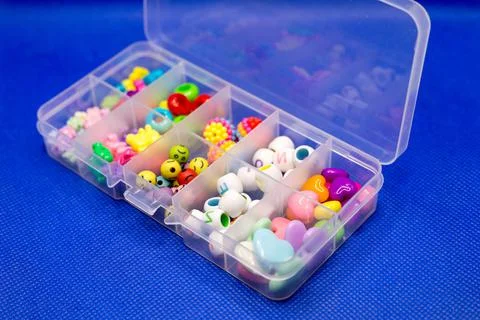 Plastic container with colored round buttons, jewelry clothes in separate cel Stock Photos