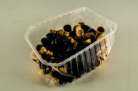 A plastic container filled with black and white chess pieces Stock Photos