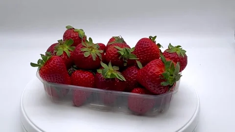 A plastic container filled with fresh ripe red strawberries on white background. Stock Footage 332587565