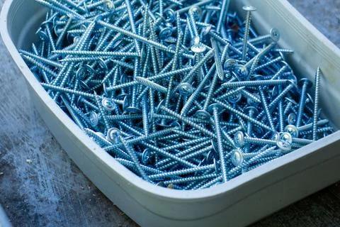 A plastic container filled with silver screws for woodworking and construction 스톡 사진