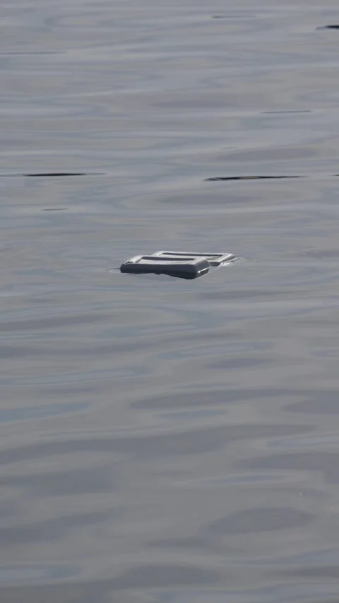 Plastic container floating on calm water with gentle ripples and no visible shor Stock Footage 343708304