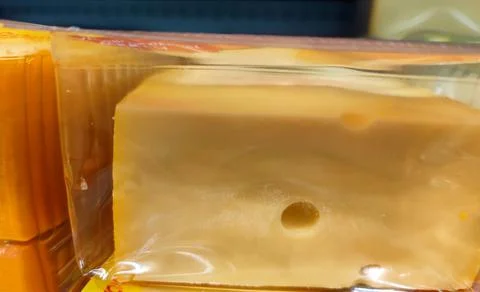 Plastic container with a large block of cheese in it is being sold without visib Stock Photos