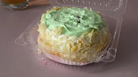 A plastic container with a pie with cream and nuts is spinning on the table Stock Footage 324698032