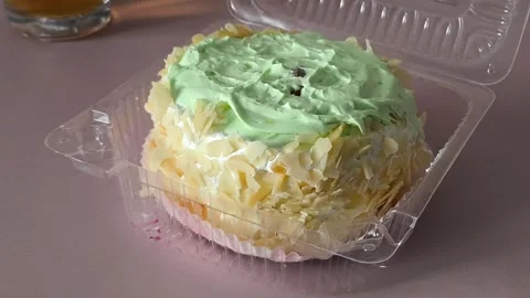 A plastic container with a pie with cream and nuts is spinning on the table Stock Footage 324698142