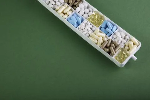 Plastic container with pills on green background Stock Photos