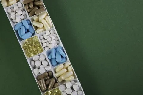 Plastic container with pills on green background Stock Photos