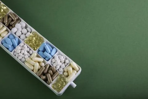 Plastic container with pills on green background Stock Photos
