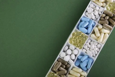 Plastic container with pills on green background Stock Photos