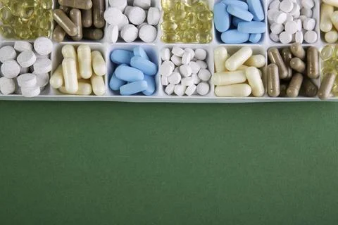 Plastic container with pills on green background Stock Photos
