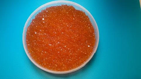 Plastic container with red salmon or keta fish caviar on blue background Stock Photos