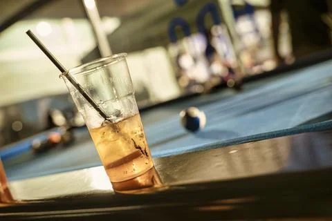 Plastic cup with alcoholic beverage resting on edge of pool table Stock Photos