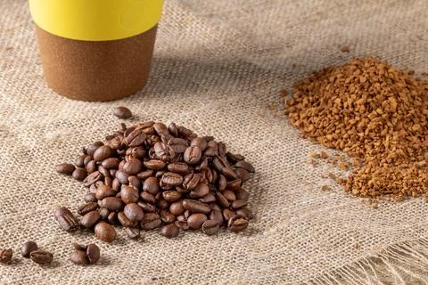 Plastic cup for coffee and heaps of coffee beans and instant coffee granules on Stock Photos