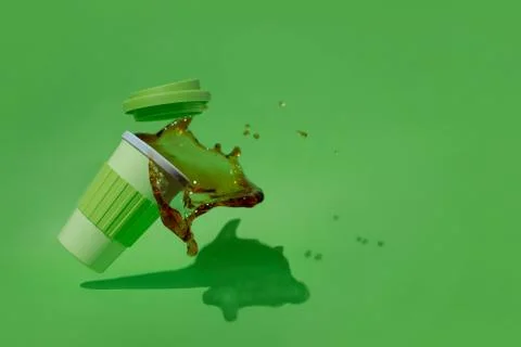 Plastic cup of coffee falling and spilled on a green background. Stock Photos