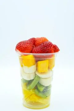 Plastic cup with cut fruit, ice cream, cream and syrup Stock Photos