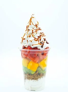 Plastic cup with cut fruit, ice cream, cream and syrup Stock Photos