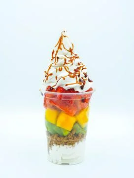 Plastic cup with cut fruit, ice cream, cream and syrup Stock Photos