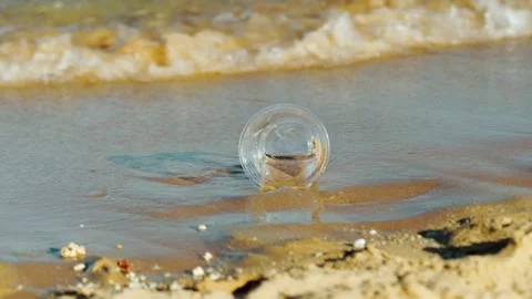 A plastic cup discarded by people on a sandy beach by the sea. 스톡 동영상 330062117