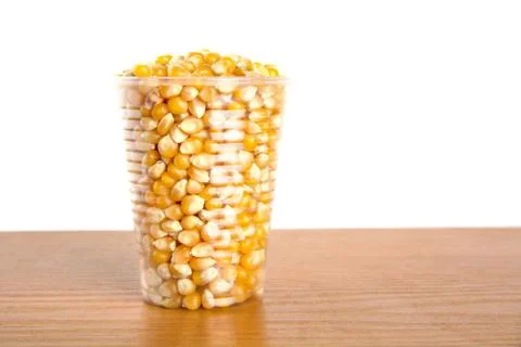 Plastic cup full of corn seeds on white background. Stock Photos
