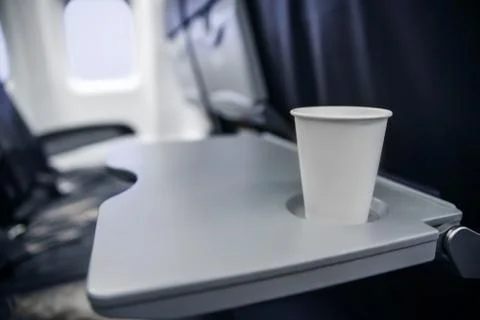 Plastic cup on the table in the plane during the flight. alcohol consumption  Stock Photos