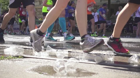 Plastic cups and a puddle of water and legs of running marathon runners Stock Footage 89830612