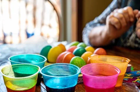 Plastic cups for dying Easter eggs with finish carton in the background. Stock Photos