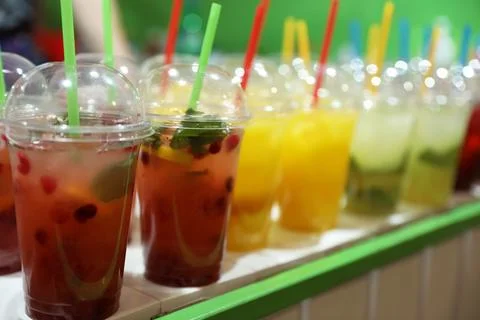Plastic cups with refreshing drinks on bar counter Stock Photos