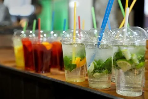 Plastic cups with refreshing drinks on bar counter Stock Photos