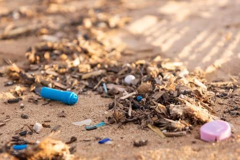 Plastic debris and microplastics mixed with organic matter lie on sand. Bro.. 스톡 사진