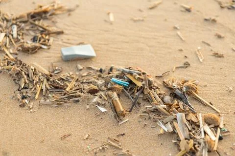 Plastic debris and microplastics mixed with organic matter lie on sand. Bro.. 스톡 사진