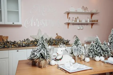 A plastic deer sits on a table with plastic Christmas trees on a wooden table Stock Photos