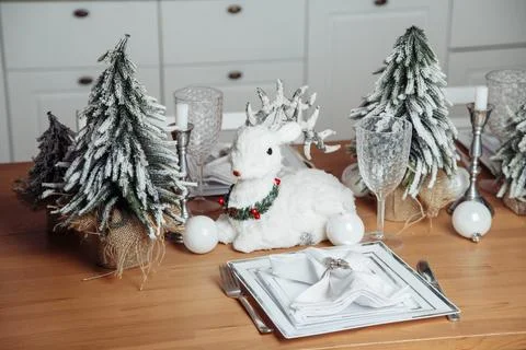 A plastic deer sits on a table with plastic Christmas trees on a wooden table Stock Photos
