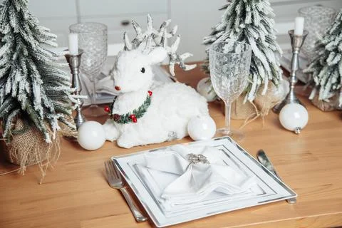 A plastic deer sits on a table with plastic Christmas trees on a wooden table Stock Photos