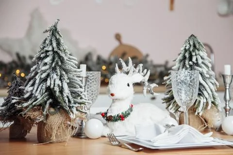 A plastic deer sits on a table with plastic Christmas trees on a wooden table Stock Photos