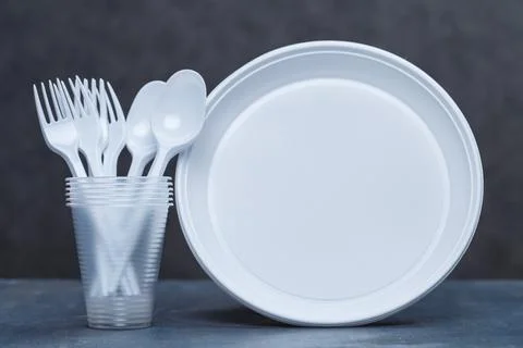 Plastic dishes, disposable tableware, plates, glasses, spoons, forks on a gra Foto stock