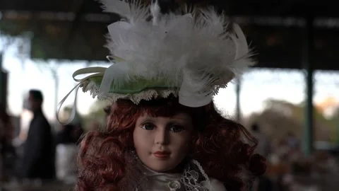 Plastic doll with feather hat swaying in the wind on sale at the flea market Video stock 142662112