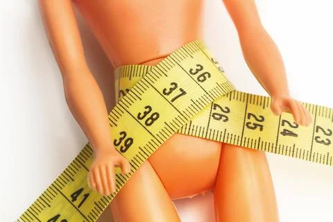 A plastic doll with a measuring tape in its waist Stock Photos