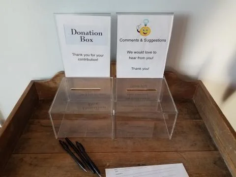 Plastic donation and comment box with pen and paper on desk Stock Photos