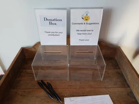 Plastic donation and comment box with pen and paper on desk Stock Photos