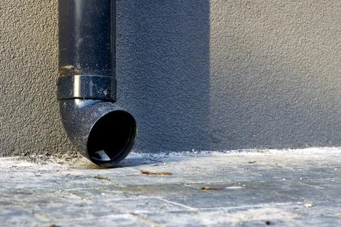 Plastic drain pipe on a gray plastered wall.Rain runoff. Stock Photos