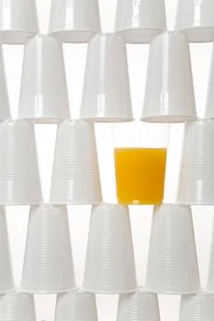 Plastic drinking cups and a glass of orange juice Foto stock