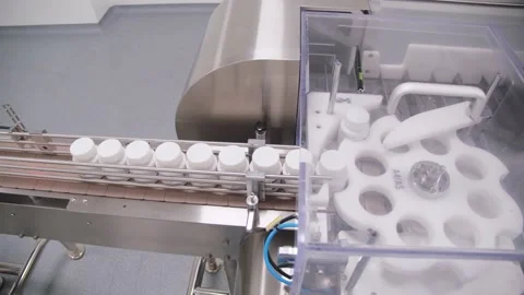 Plastic drug vials are moving through the sorting drum on assembly line Stock Footage 200857055