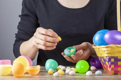 Plastic easter eggs being filled with chocolates before easter egg hunt. Stock Photos